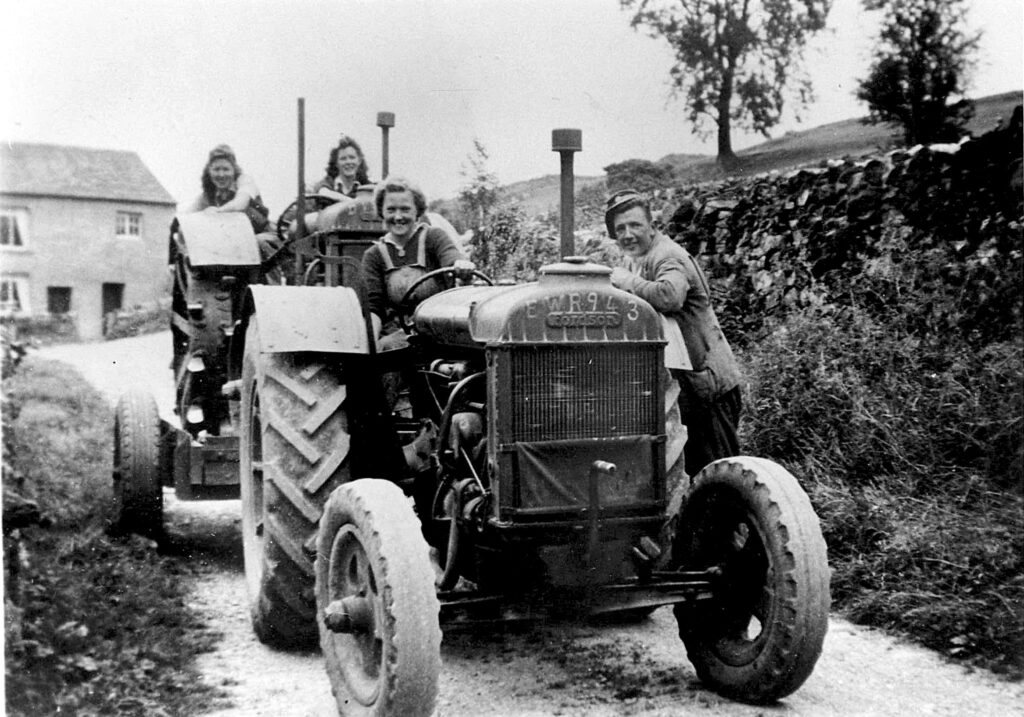 Black and white photo of women driving two tractors