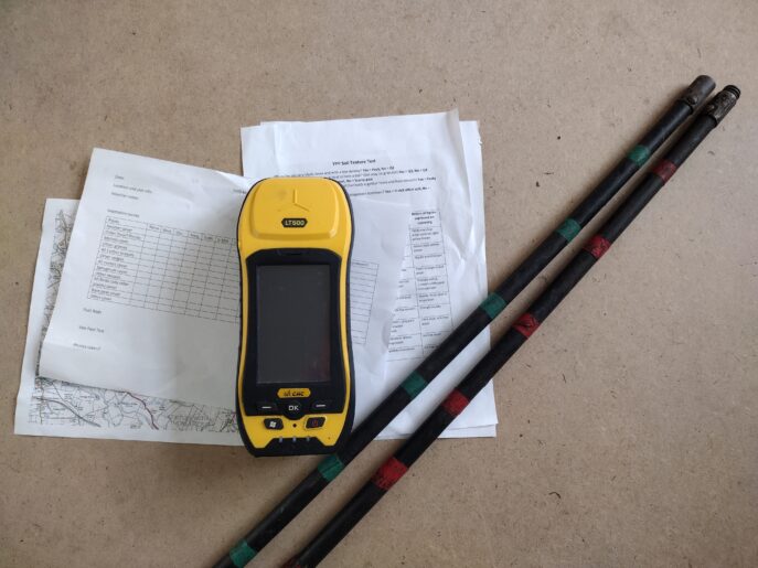 Photo showing GPS mapper, ranging poles and paper recording sheets