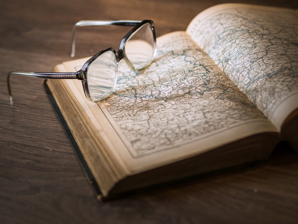 Photograph of an open alas with a map and a pair of reading glasses