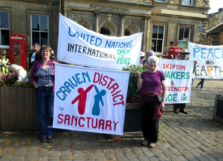 People holding handmade banners including one that says "Craven District of Sanctuary"