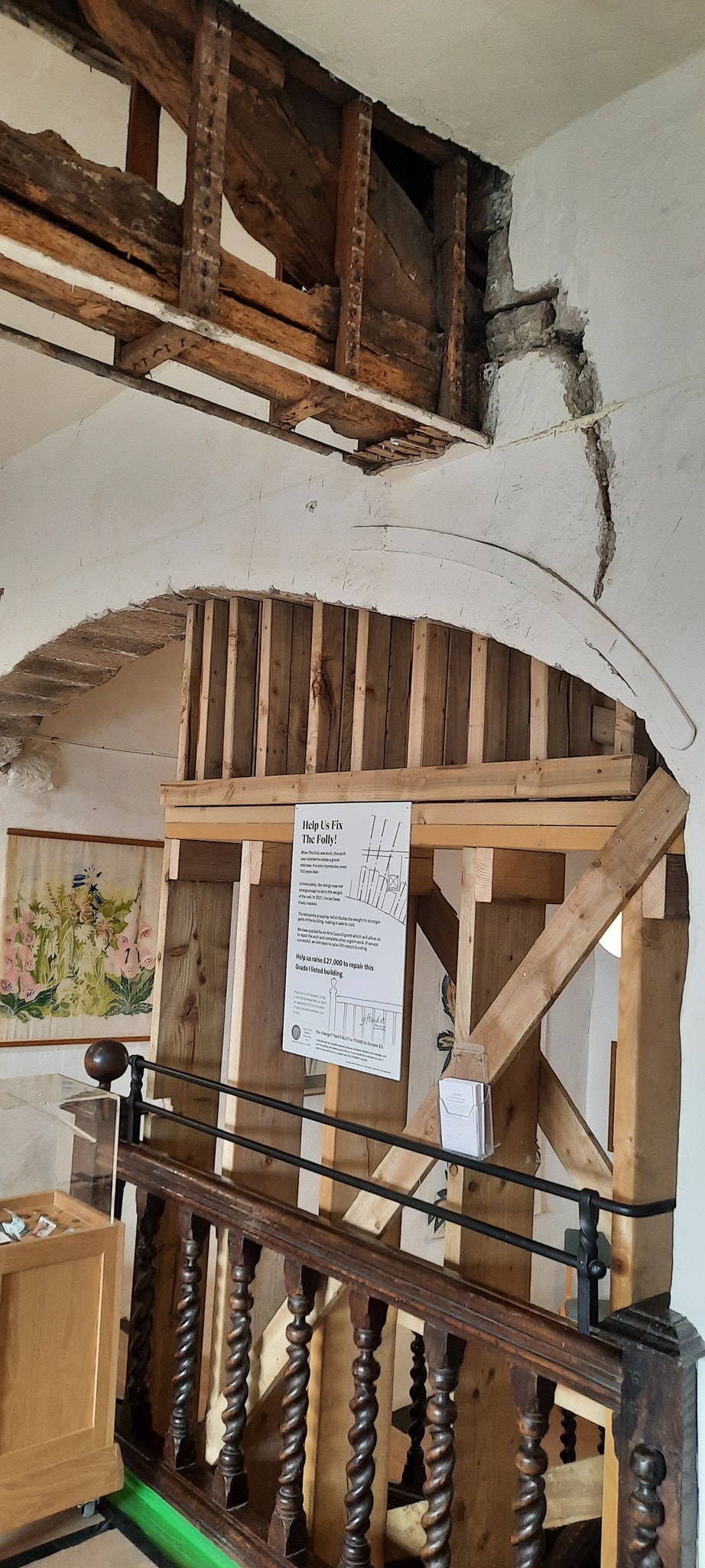 Arch above a staircase supported by wooden propping. A large crack appears in the face of the wall above the arch, with a worm-eaten timber truss above it.